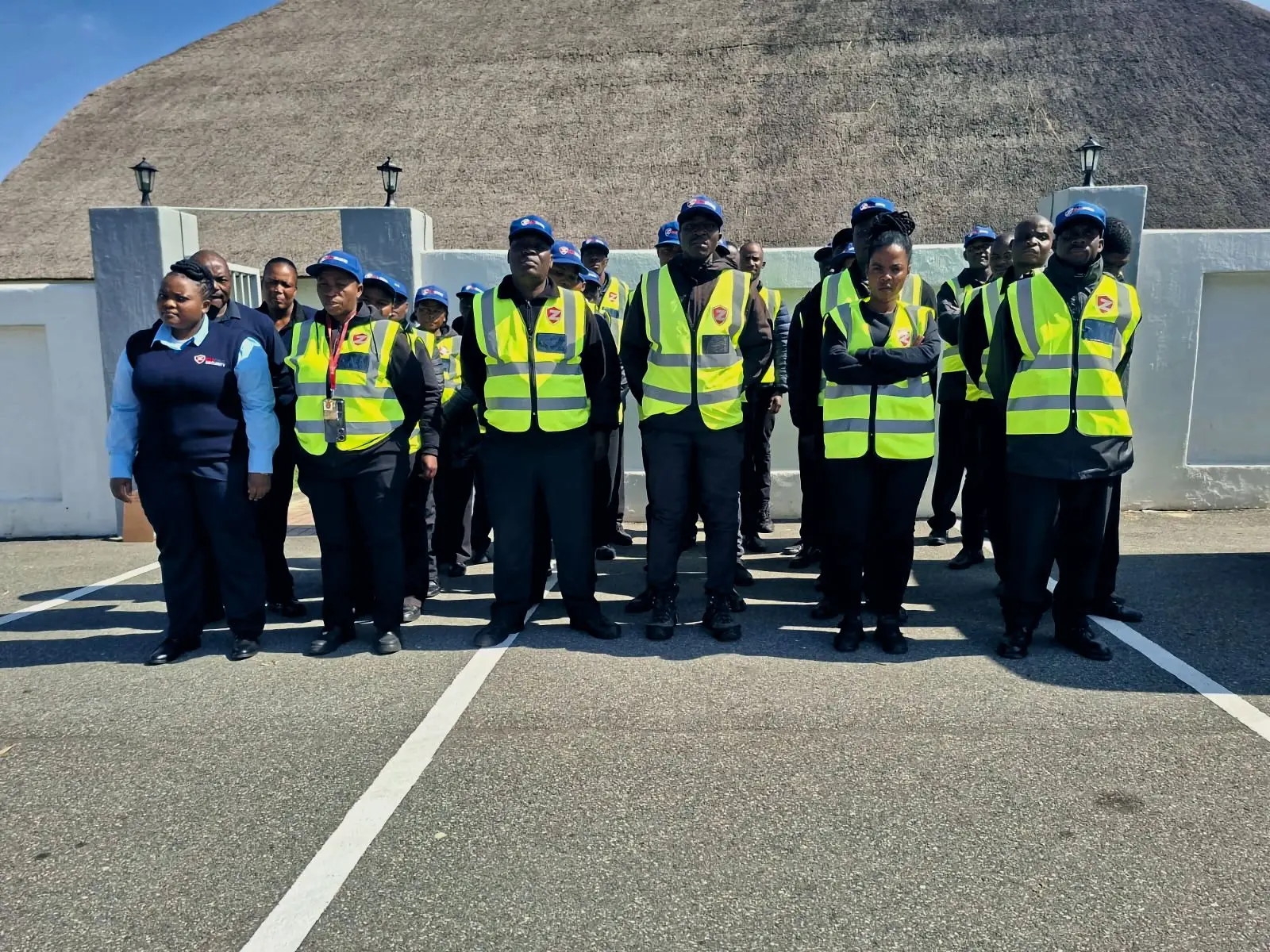 A large ZENOSC team in hi-vis vests outside a thatched venue