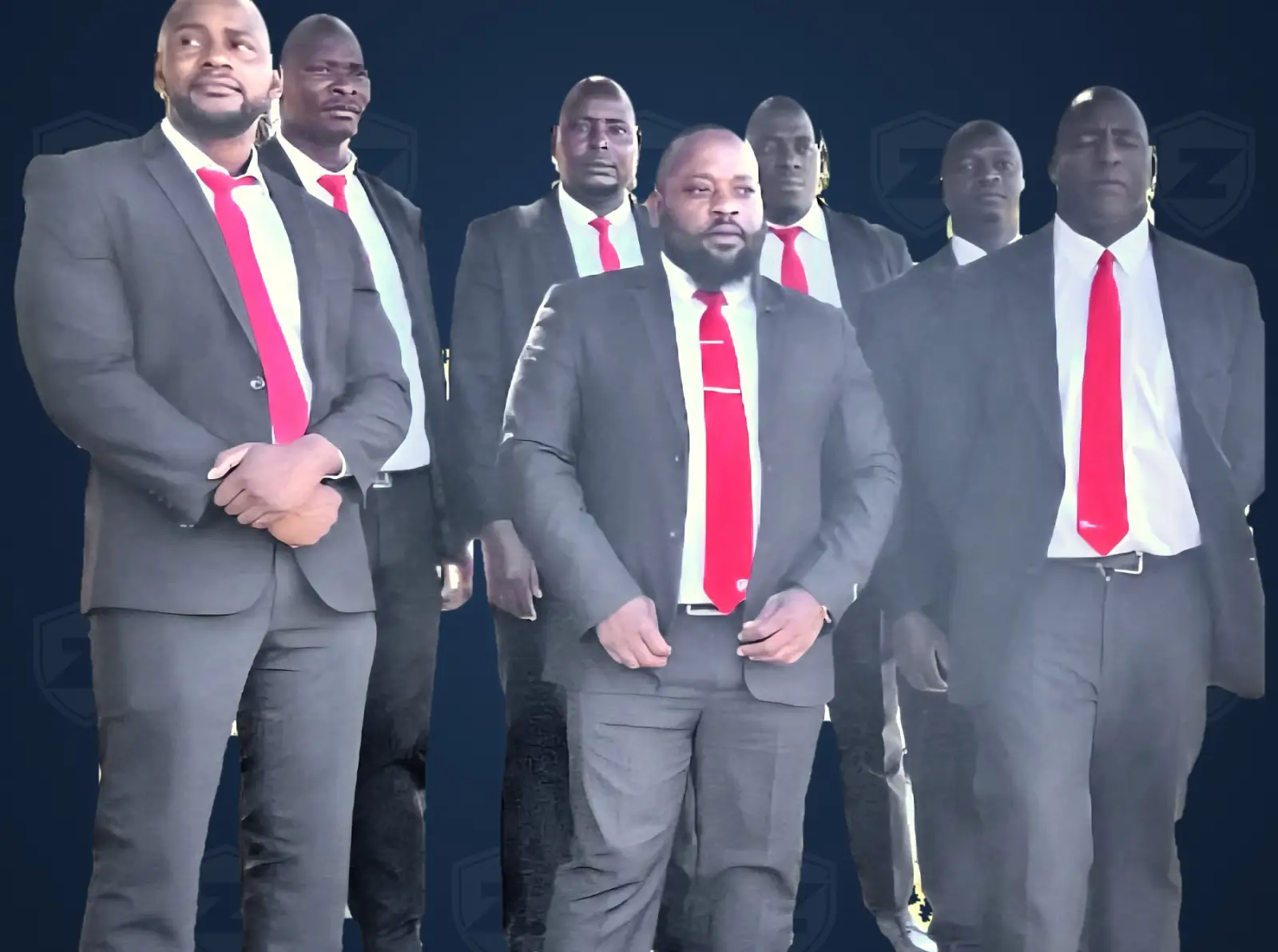 Seven ZENOSC protection officers in dark suits and red ties on a navy ZENOSC backdrop